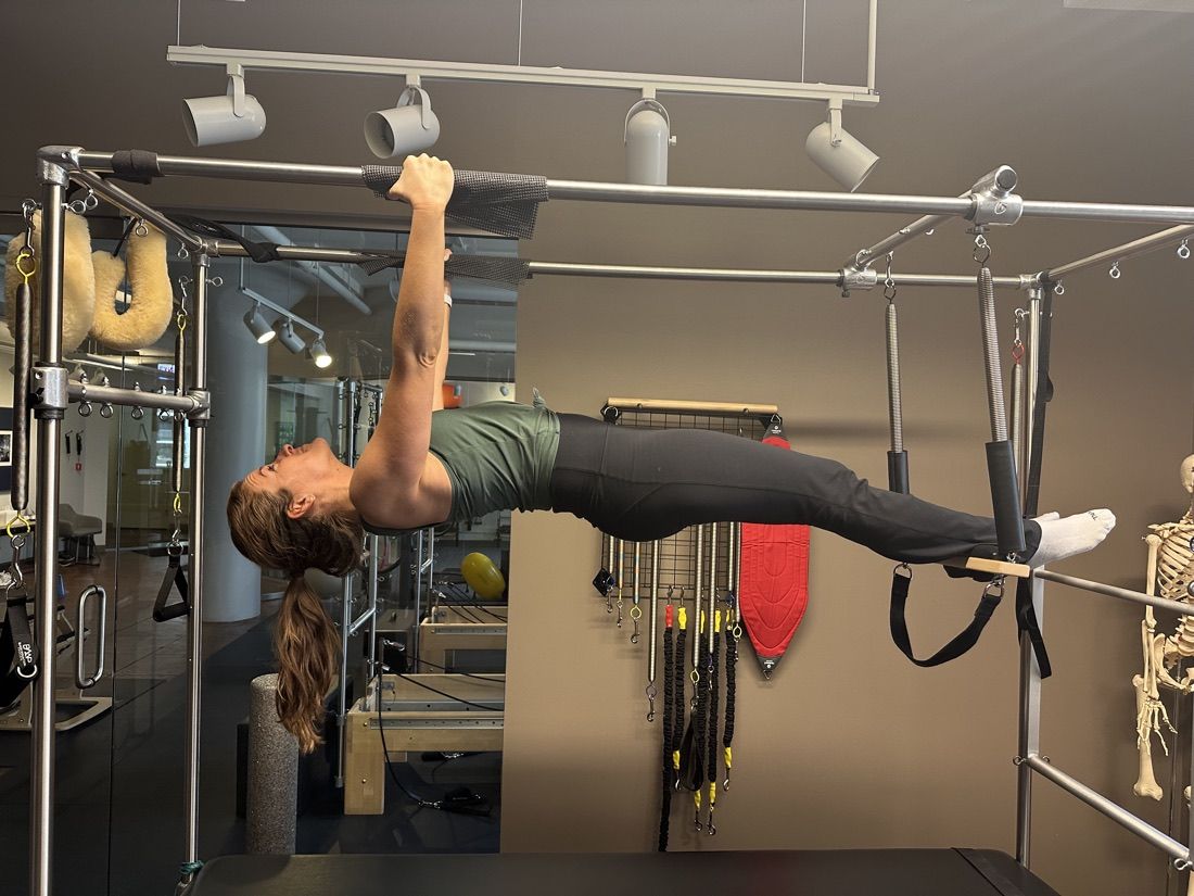 A client performing a controlled inverted strength hold on the Cadillac under coach guidance