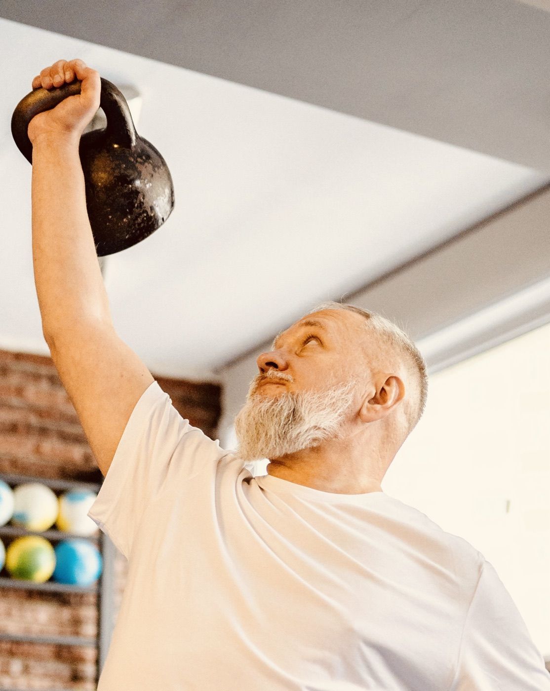 A long-time client pressing a kettlebell overhead inside the Movement Med studio