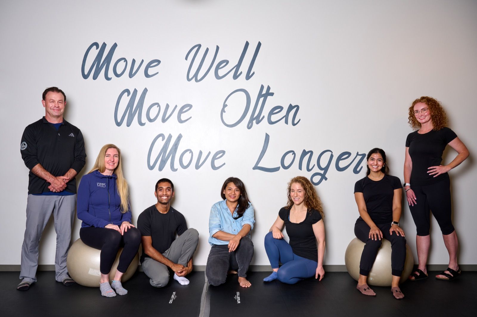 The Movement Med team in the Streeterville studio, in front of the ‘Move Well · Move Often · Move Longer’ wall.